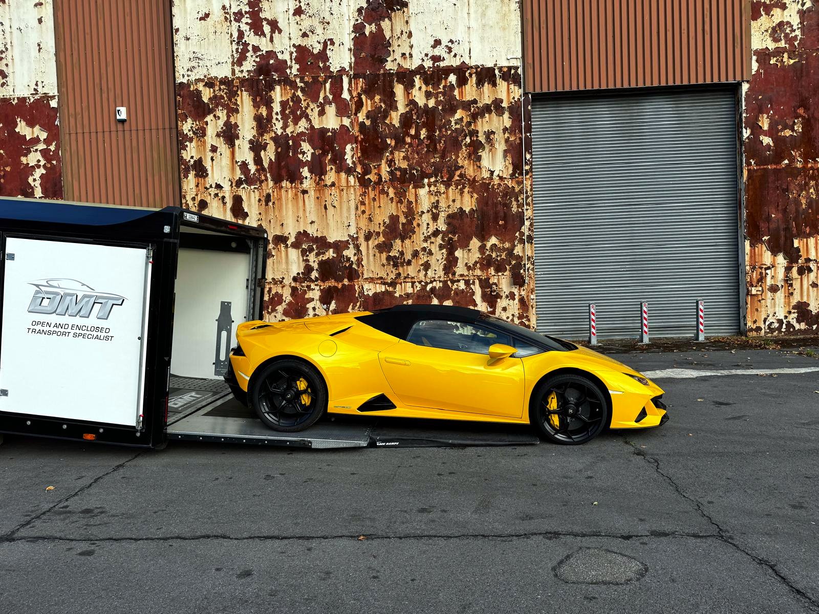 Yellow Lamborghini Huracán beside the branded DMT enclosed transporter